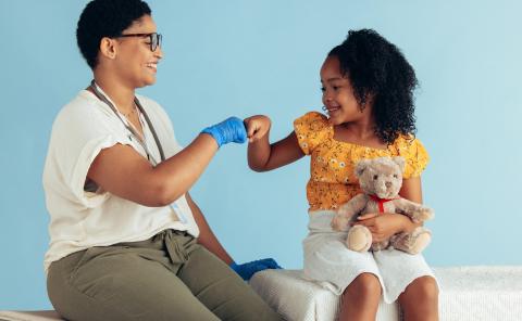 Clinician and her young patient fist bump.