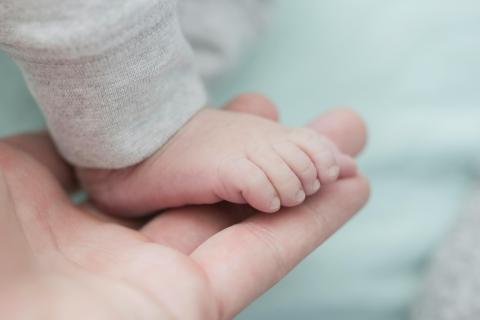 A baby's foot held in their parent's hand. Used to show the value of rapid genomic testing for critically unwell babies.